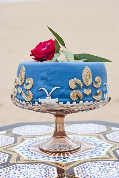 Gâteau de mariage bleu sur une table et roses rouges sur le dessus dans le paysage du désert — Photo