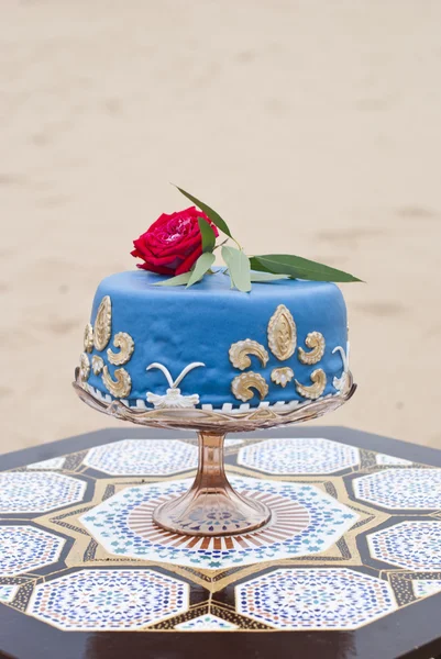 砂漠の風景の上にテーブルと赤いバラにブルーのウェディング ケーキ — ストック写真