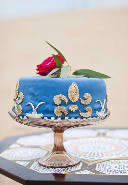 Pastel de boda azul en una mesa y rosas rojas en la parte superior en el paisaje del desierto —  Fotos de Stock