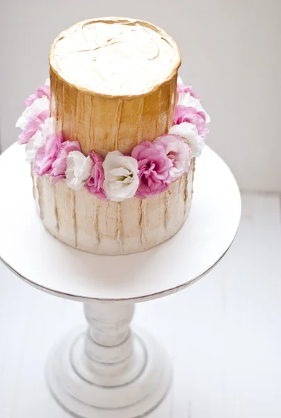 Guld och vit bröllopstårta och rosa blommor runt — Stockfoto