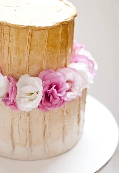 Ouro e branco bolo de casamento e flores cor de rosa ao redor — Fotografia de Stock