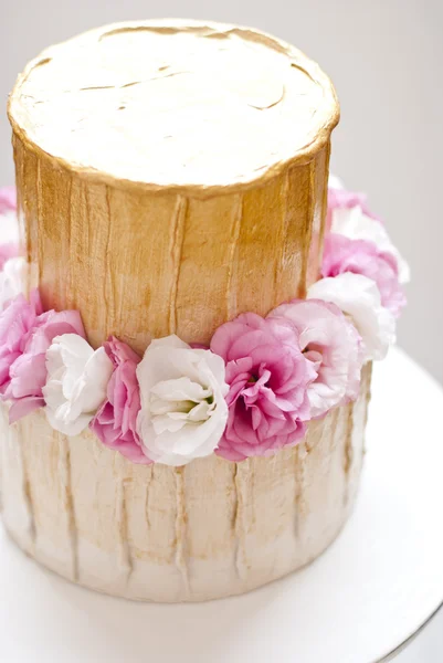 Gâteau de mariage or et blanc et fleurs roses autour — Photo