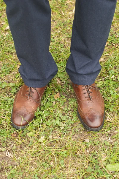 Νέος μόδα στα πόδια του ανθρώπου σε μπλε τζιν και μπότες καφέ στο γρασίδι — Φωτογραφία Αρχείου
