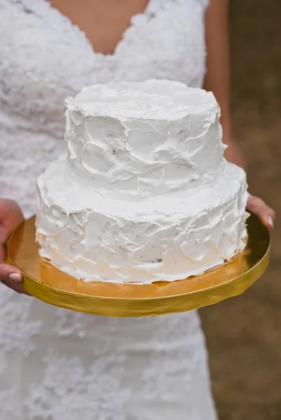 white wedding cake in hands of the bride