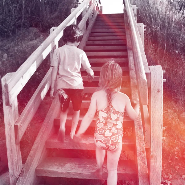 Two kids going up stairs at beach — Stock Photo, Image