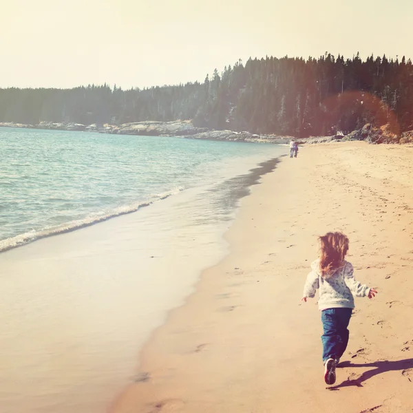 Liten flicka kör på stranden — Stockfoto