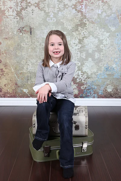 Malá dívka sedící na kufry — Stock fotografie