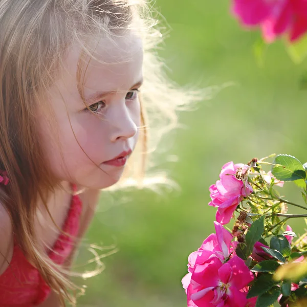 Liten flicka att lukta blommor — Stockfoto