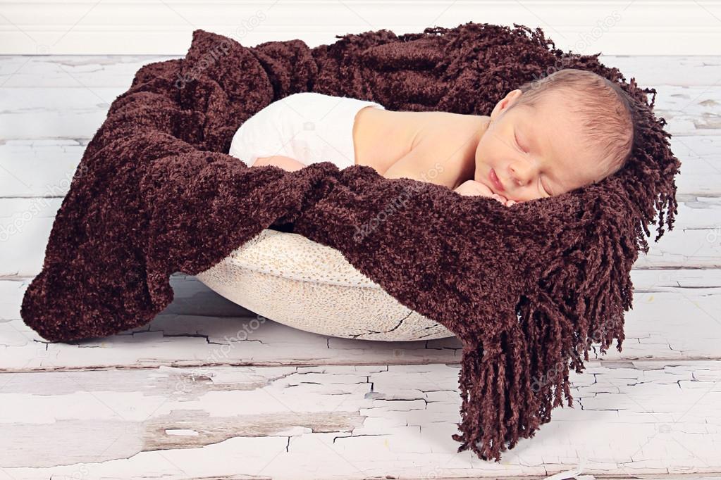 Newborn baby sleeping on brown blanket