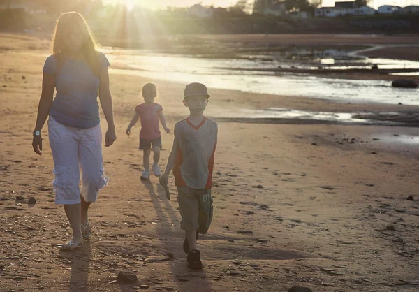 Mor och barn gå på stranden — Stockfoto