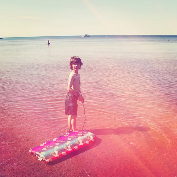 Menino brincando na água na praia — Fotografia de Stock