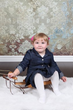 Kızakları üzerinde oturan küçük kız