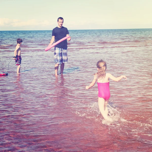 Pappa leker med barnen på stranden — Stockfoto