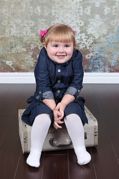 Girl sitting on suitcase — Stock Photo, Image