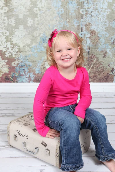 Niña sentada en la maleta en el estudio — Foto de Stock