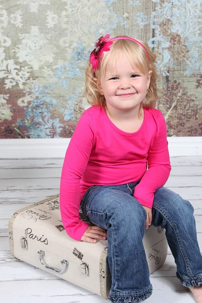 Niña sentada en la maleta en el estudio — Foto de Stock