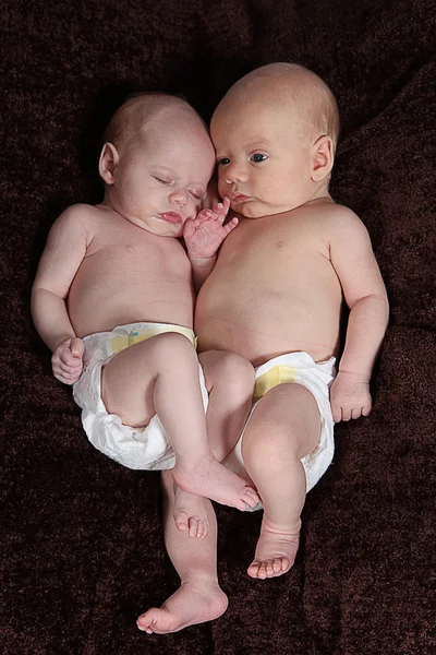 Hermano y hermana recién nacidos acostados sobre una manta marrón —  Fotos de Stock