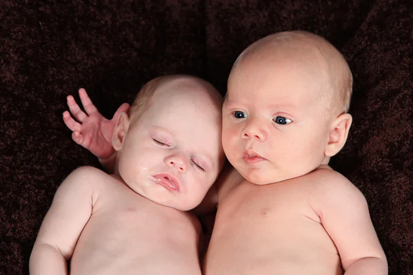 Hermano y hermana recién nacidos acostados sobre una manta marrón — Foto de Stock