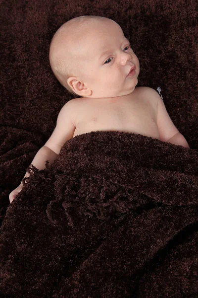 Bebé recién nacido acostado sobre una manta marrón — Foto de Stock