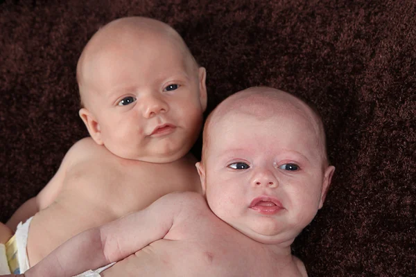 Hermano y hermana recién nacidos acostados sobre una manta marrón —  Fotos de Stock