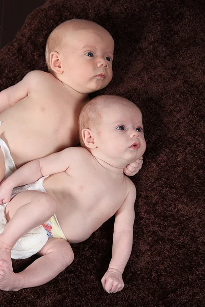 Hermano y hermana recién nacidos acostados sobre una manta marrón — Foto de Stock
