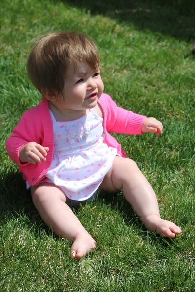 Kleines Mädchen sitzt auf Gras — Stockfoto