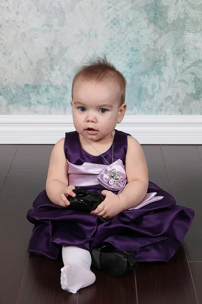 Klein meisje in jurk zittend op de vloer — Stockfoto