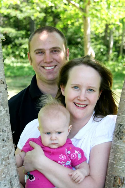 Young family together near trees — Stock Photo, Image