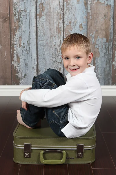 Cute boy sitting on suitcase — Stock Photo, Image