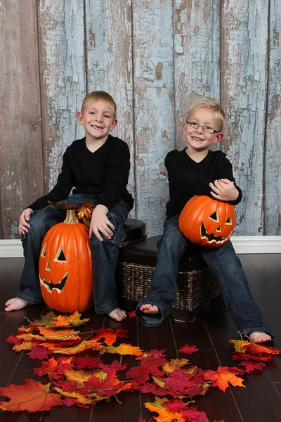 Niños con calabazas de halloween y hojas amarillas — Foto de Stock