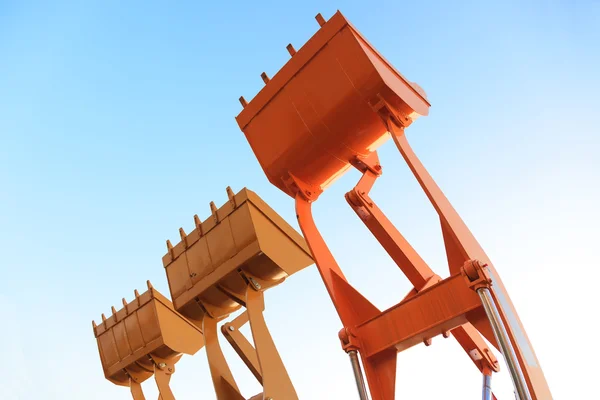 The buckets of heavy construction machine raised against — Stock Photo, Image