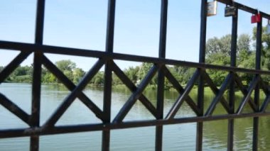 Yeşil ağaçlı bir park siyah metal kafes çitinden görülebilir.