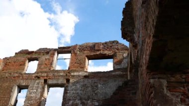 Çatısı olmayan eski terk edilmiş kırmızı tuğla bina. Beyaz bulutlu mavi gökyüzü