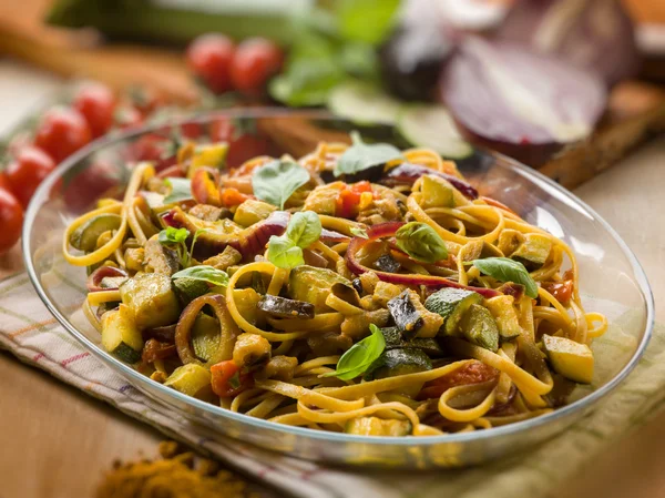 Pasta with eggplants zucchinis tomatoes and curry, selective foc — Stock Photo, Image