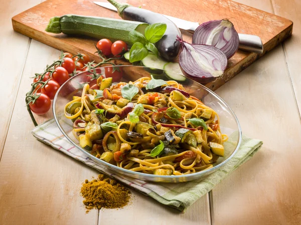 Pasta with eggplants zucchinis tomatoes and curry Royalty Free Stock Images