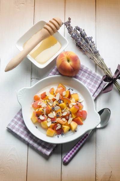 Fruit salad with peach almond honey and lavender flower — Stock Photo, Image