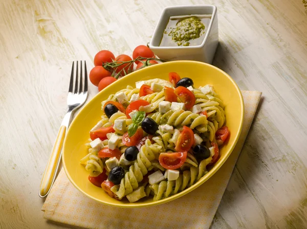 Pasta salad with pesto feta tomatoes and black olives — Stock Photo, Image