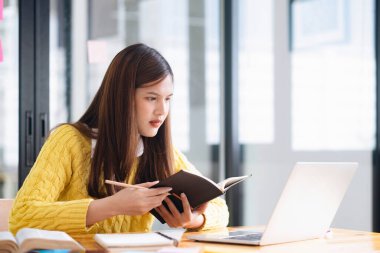 Bilgisayar ve mobil cihaz kullanan genç bir kolaj öğrencisi. Eğitim ve çevrimiçi öğrenim. 