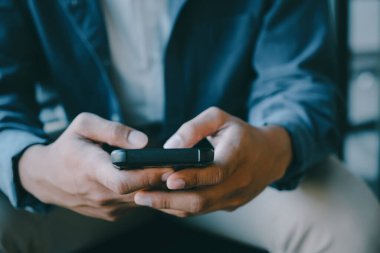 Genç adam cep telefonu kullanıyor. İş, eğitim ve iletişim için çevrimiçi bağlantı teknolojisi kullanılıyor. 