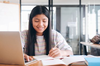 Neşeli çocuk çevrimiçi öğrenim için bilgisayar kullanarak heyecanlanıyor. Çevrimiçi eğitim ve kendi kendine öğrenim ve evde eğitim kavramı.