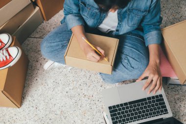 Müşteri, nakliyat ve lojistik, tüccar ve satıcı, işyeri sahibi veya sme, çevrimiçi alışveriş için paket kutusuna adres yazan genç bir kadın..