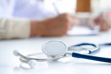 Steteskop ve klipsli pano arka planda doktorların çalıştığı yerde, doktor internet üzerinden uzaktan tıbbi danışmanlık yapıyor..