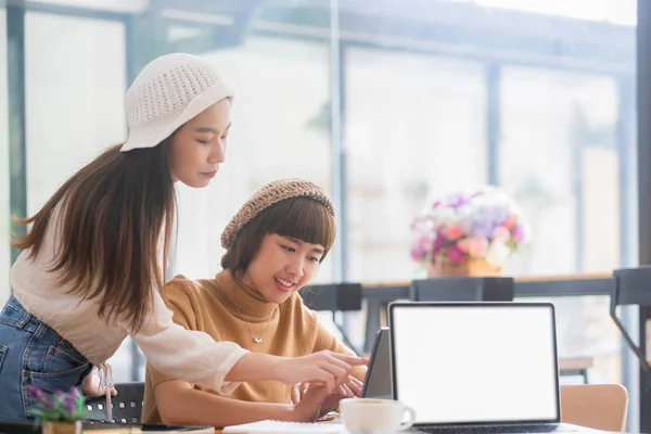 在数码平板电脑上一起工作的两名年轻女子中枪 有创意的女性高管在办公室见面时使用平板电脑 微笑着 — 图库照片