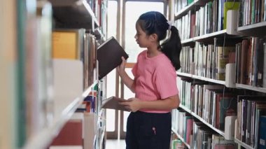 Liseli kız kütüphanede kitap seçiyor. Okumak için edebiyat seçen kız çocuğu. Kitapçıdaki çocuk. Okul eğitimi kavramı.