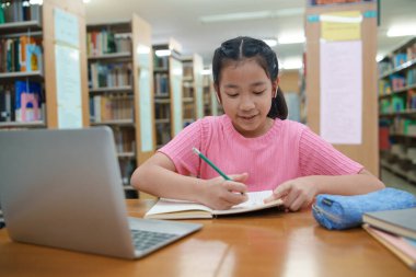Okuldaki kütüphanede bilgisayarında video kaydı olan liseli kız. Öğretmenle internetten çalışan gülümseyen kız. Asya İlköğretim Okulu 'nun portresi kütüphanede oturmuş video görüşmesi yapıyor.