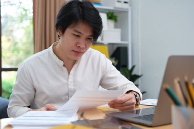 İş planlama, çevrimiçi öğrenme, veri analizi ve proje yönetimi için dijital araçlar kullanan Asyalı adam.