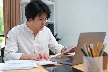 İş adamı ya da muhasebeci mali veri raporunu, muhasebe belgesini ve ofisteki dizüstü bilgisayarını, iş konseptini hesaplamak için hesap makinesine el attı