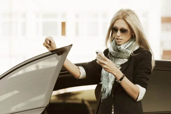 Fashion business woman calling on mobile phone at the car