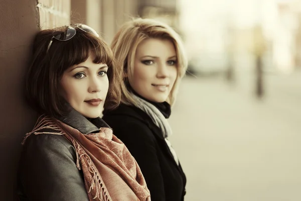 Two happy young fashion women on the city street