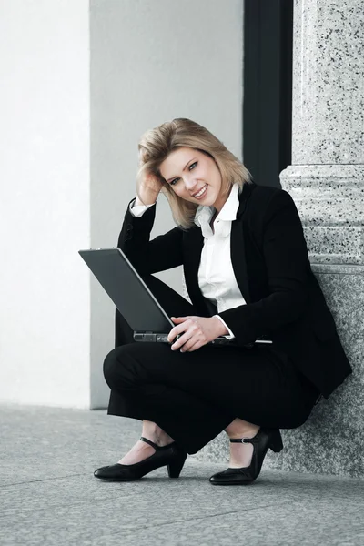 Young businesswoman using laptop outdoor